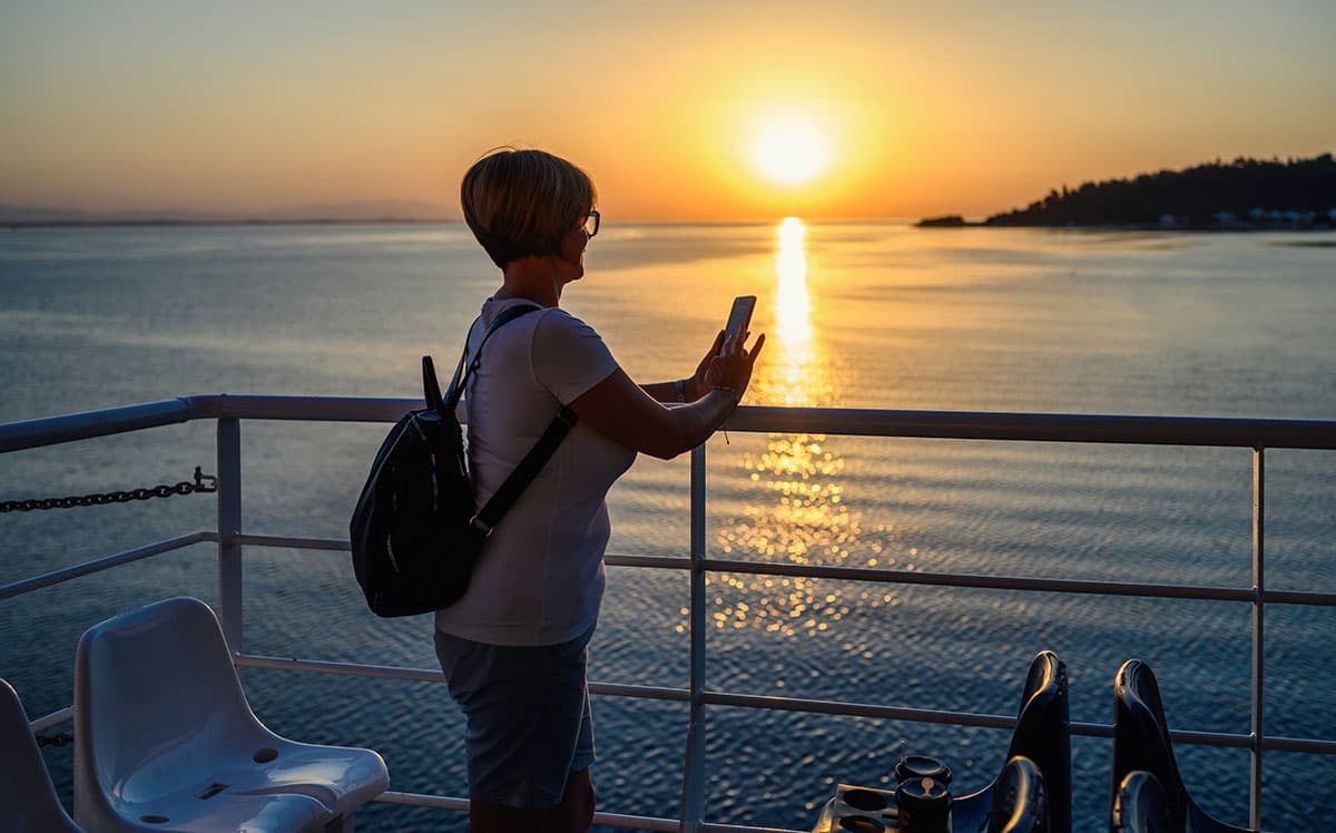 Traveler enjoying sunset views from a ferry deck during a sea crossing.
