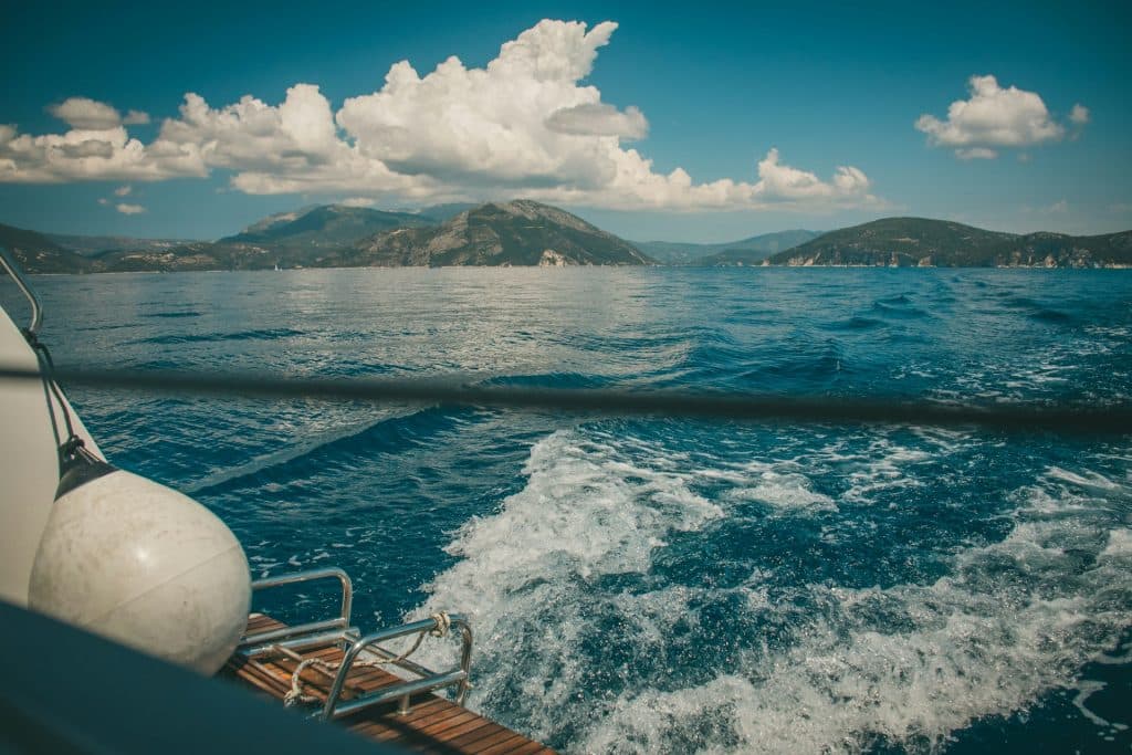 A boat traveling on a body of water with mountains in the background