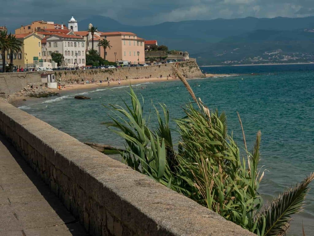 A coastal scene with pastel-colored buildings overlooking a calm, turquoise sea