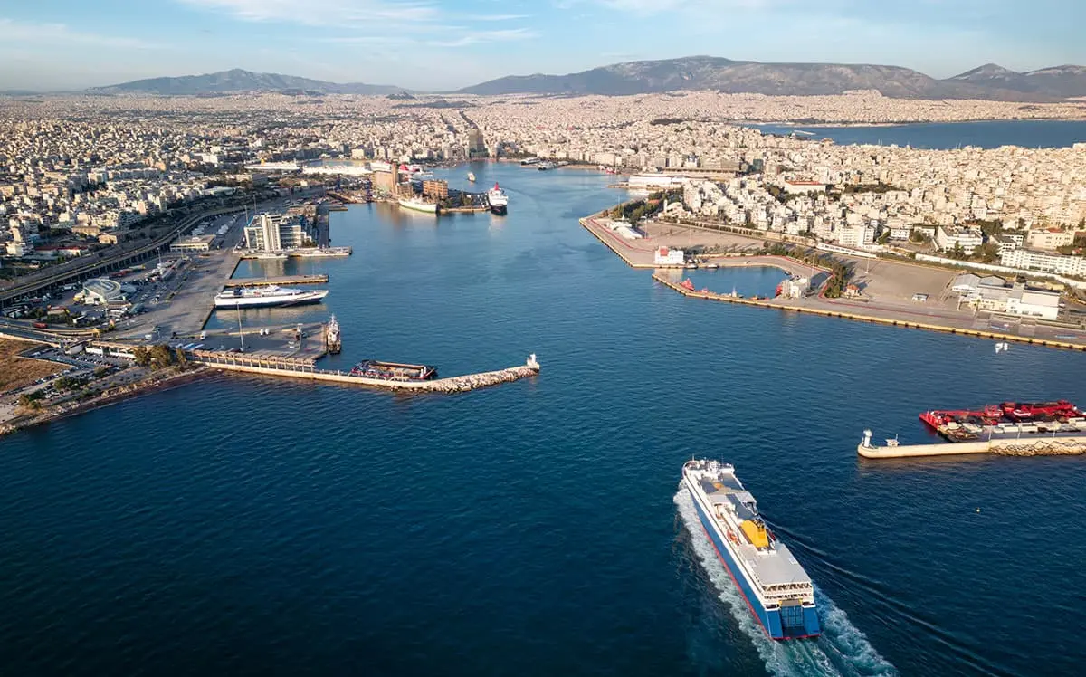 Aerial view of a large ferry approaching a busy passenger port in a coastal city.
