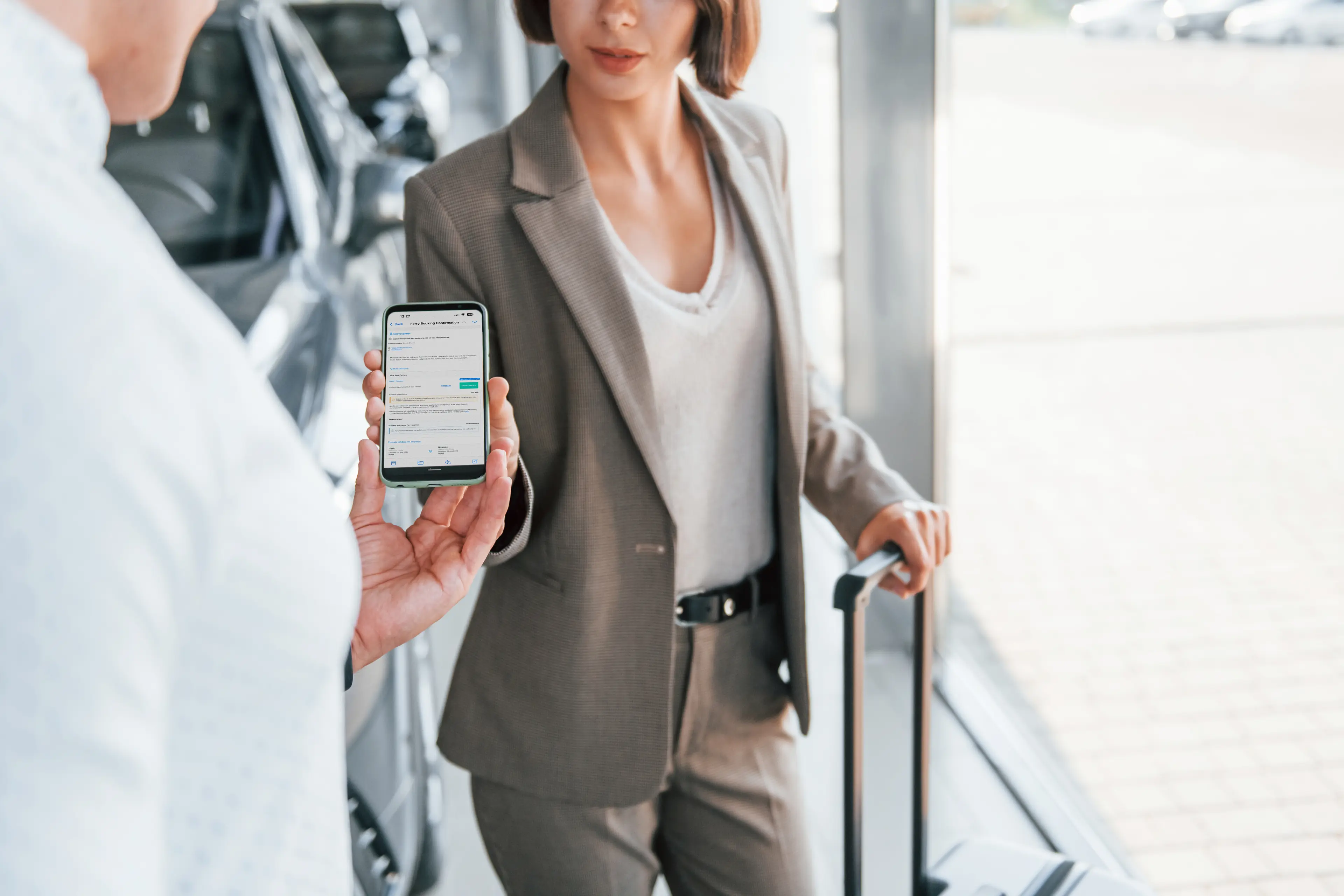 Una mujer con un smartphone mostrando la página de confirmación de reserva de ferryscanner.com, que simboliza la facturación digital y el embarque para viajar en ferry.